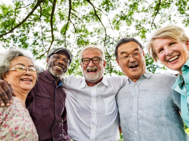 Five older adults smiling in woods