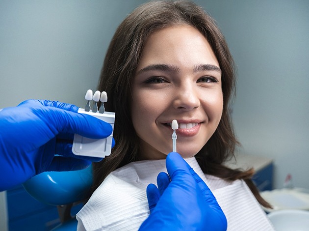Dentist holding sample veneers to a woman’s smile