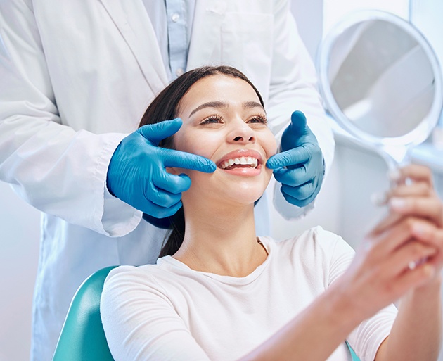 Woman admiring the results of teeth whitening in handheld mirror