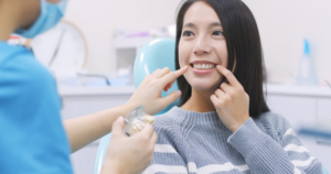 Close up of woman sitting in dental chair while she and dentist point at her teeth