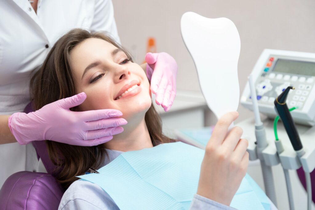 Woman in dental chair admiring her  cosmetic treatment results